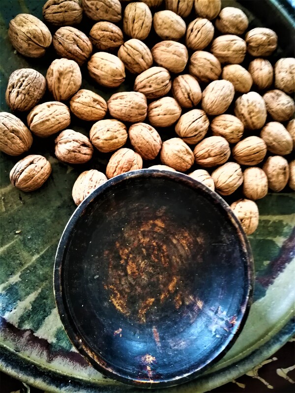 Empty wooden bowl on green table with walnuts