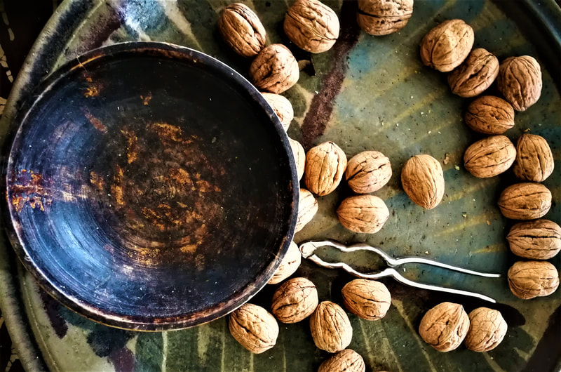 Empty wooden bowl on green table with strategically placed walnuts and nutcracker