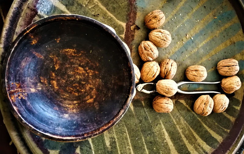 empty wooden bowl on green table with a few walnuts and a nutcracker