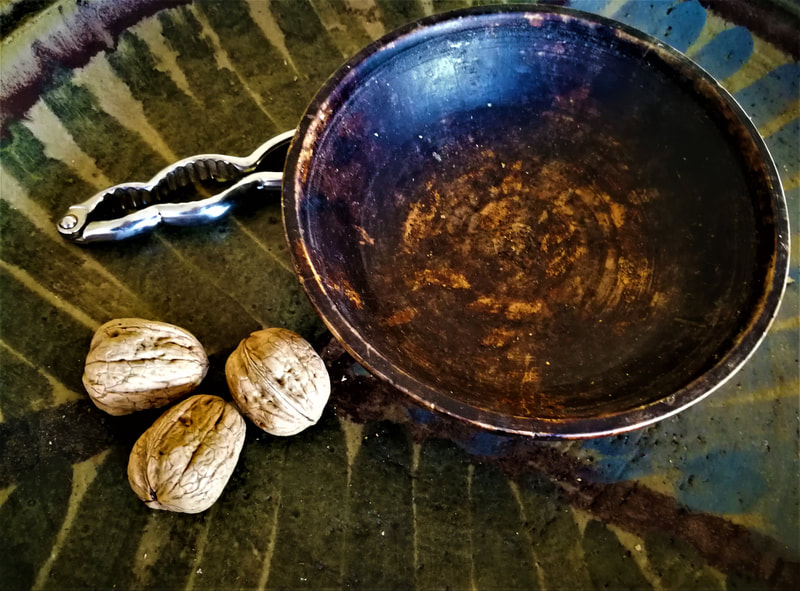 Empty wooden bowl on green table with three walnuts and a nutcracker